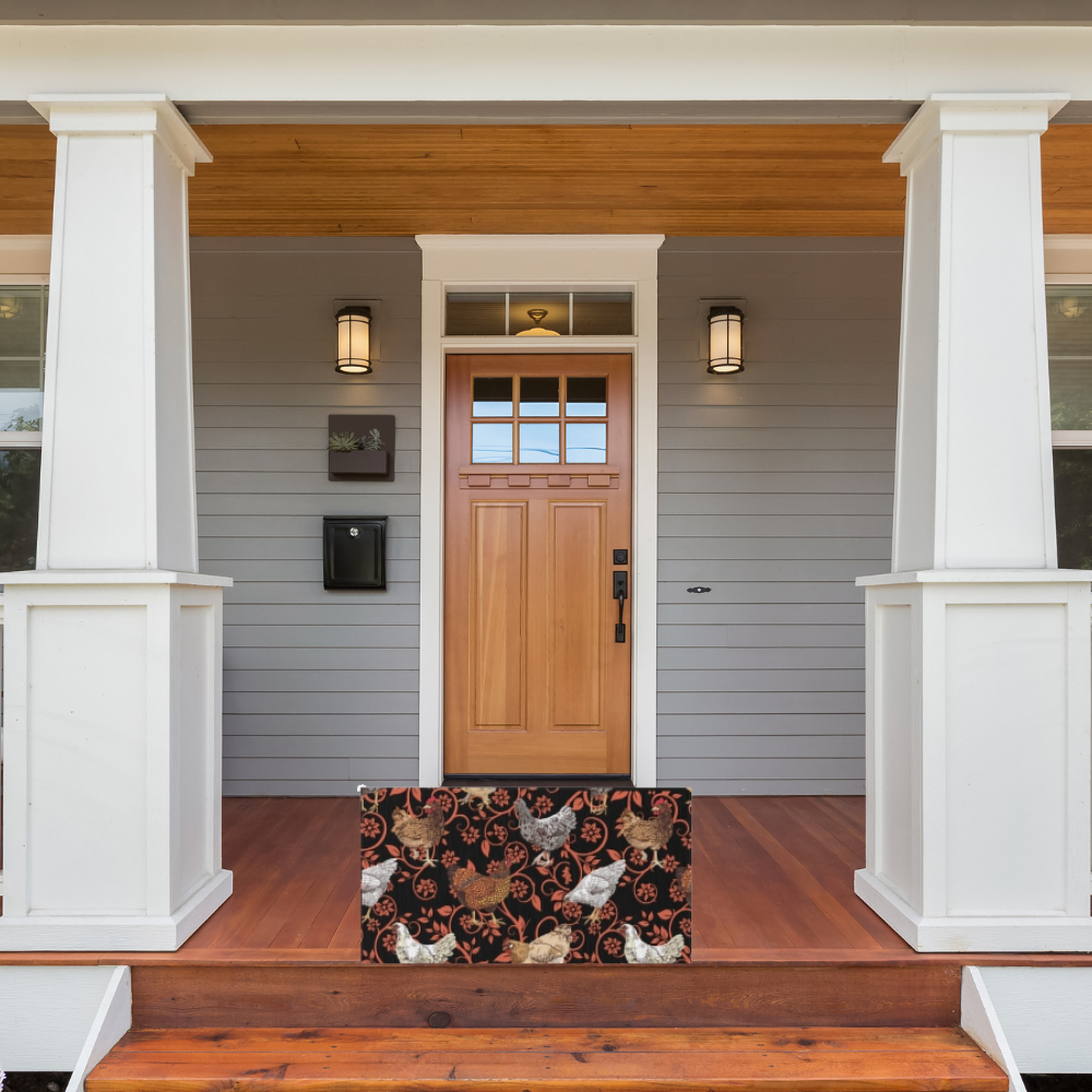 Front door of a house with a decorative doormat featuring chicken patterns on a wooden porch.