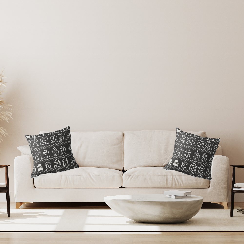 White sofa with decorative pillows featuring house patterns in a living room setting.