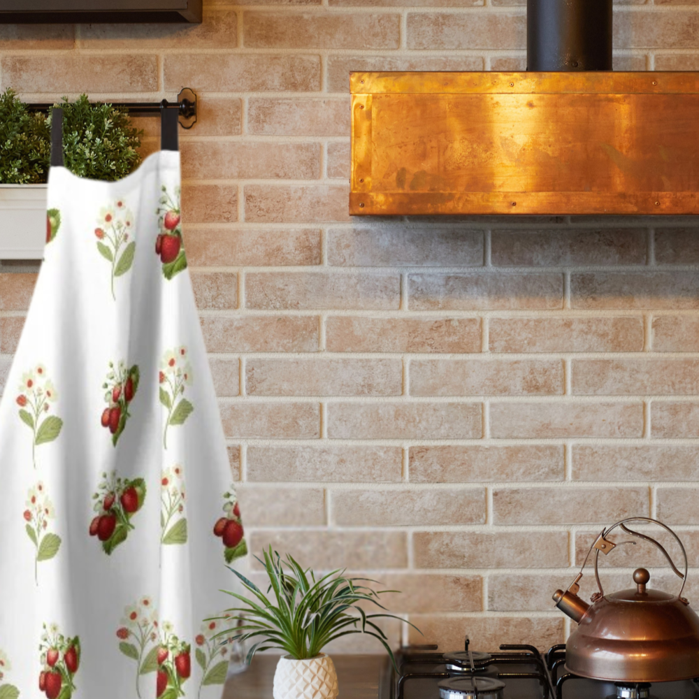 Vintage inspired strawberry print apron shown in a kitchen with a beautiful copper range hood