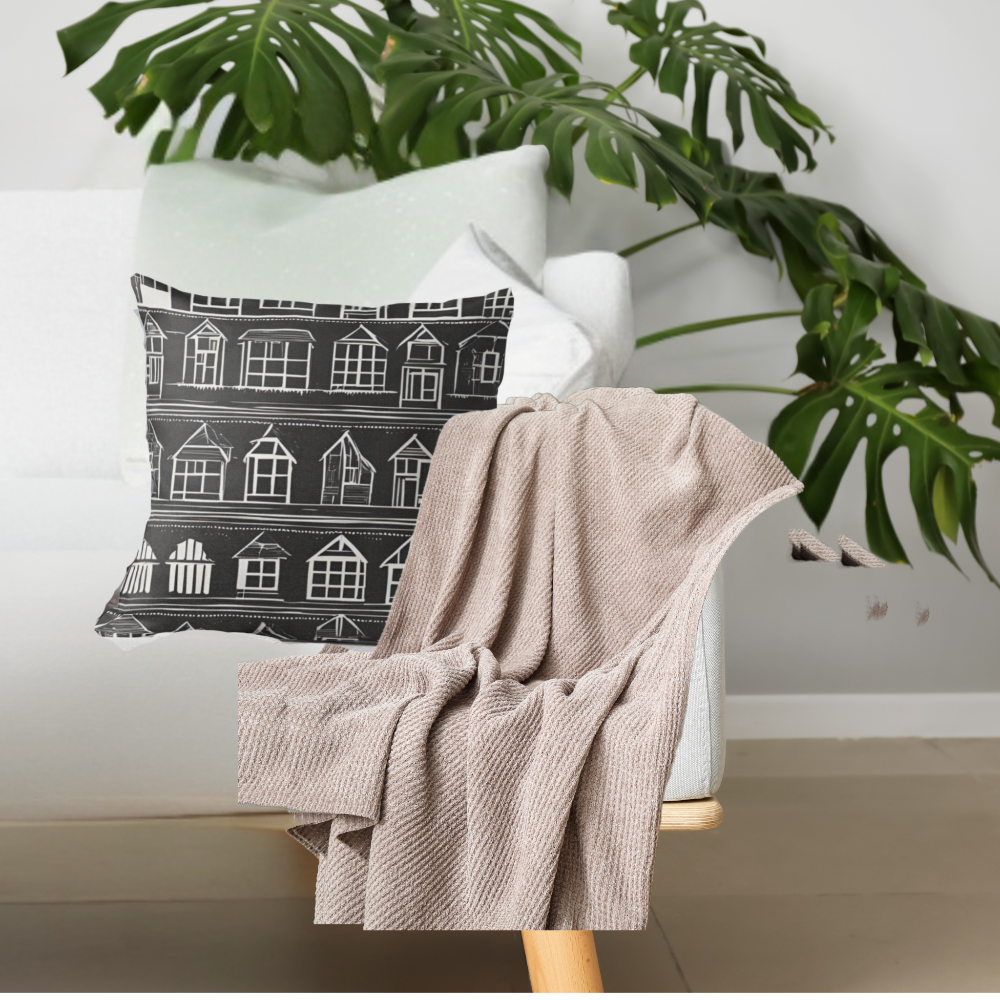 Home Sweet Home pillow with black background and white houses in rows shown on a white sofa with a large plant