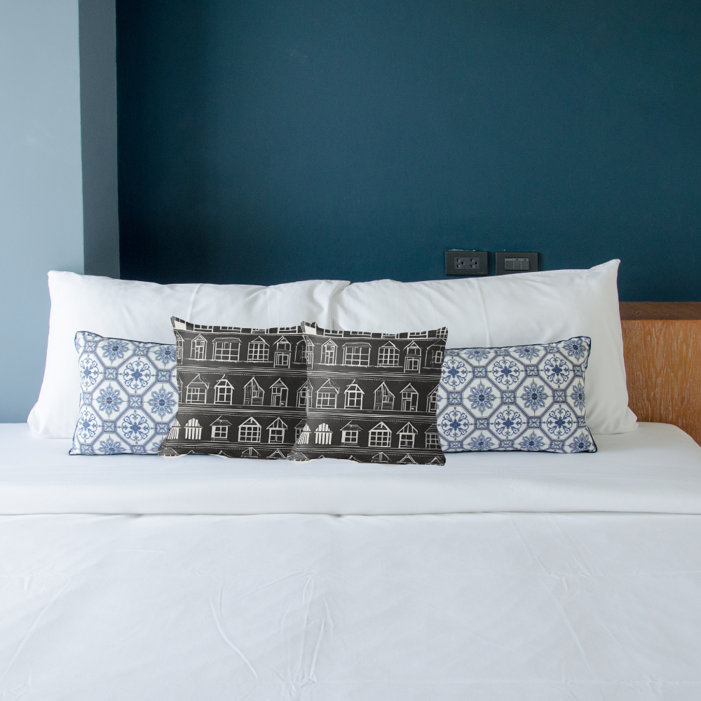 Decorative Home Sweet Home pillows on a bed with a blue wall in the background and blue pillows.