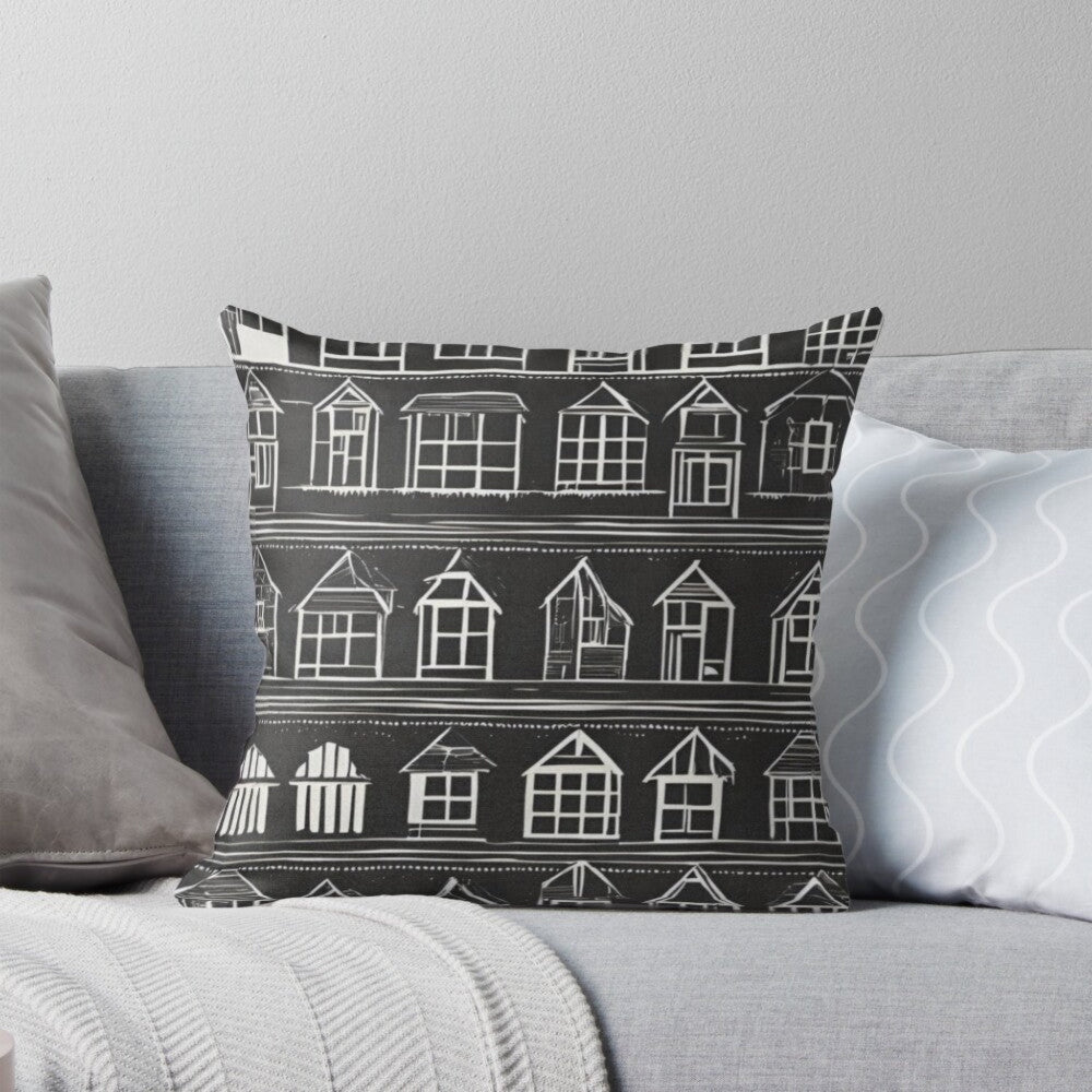 Decorative black farmhouse style pillow with house pattern in white on a gray sofa