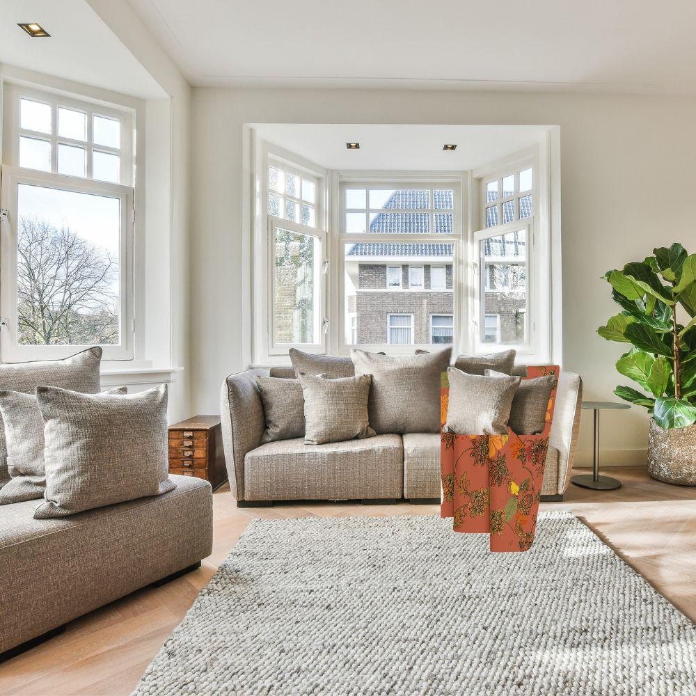 Rich, autumn toned blanket with leaf pattern shown on a comfy couch