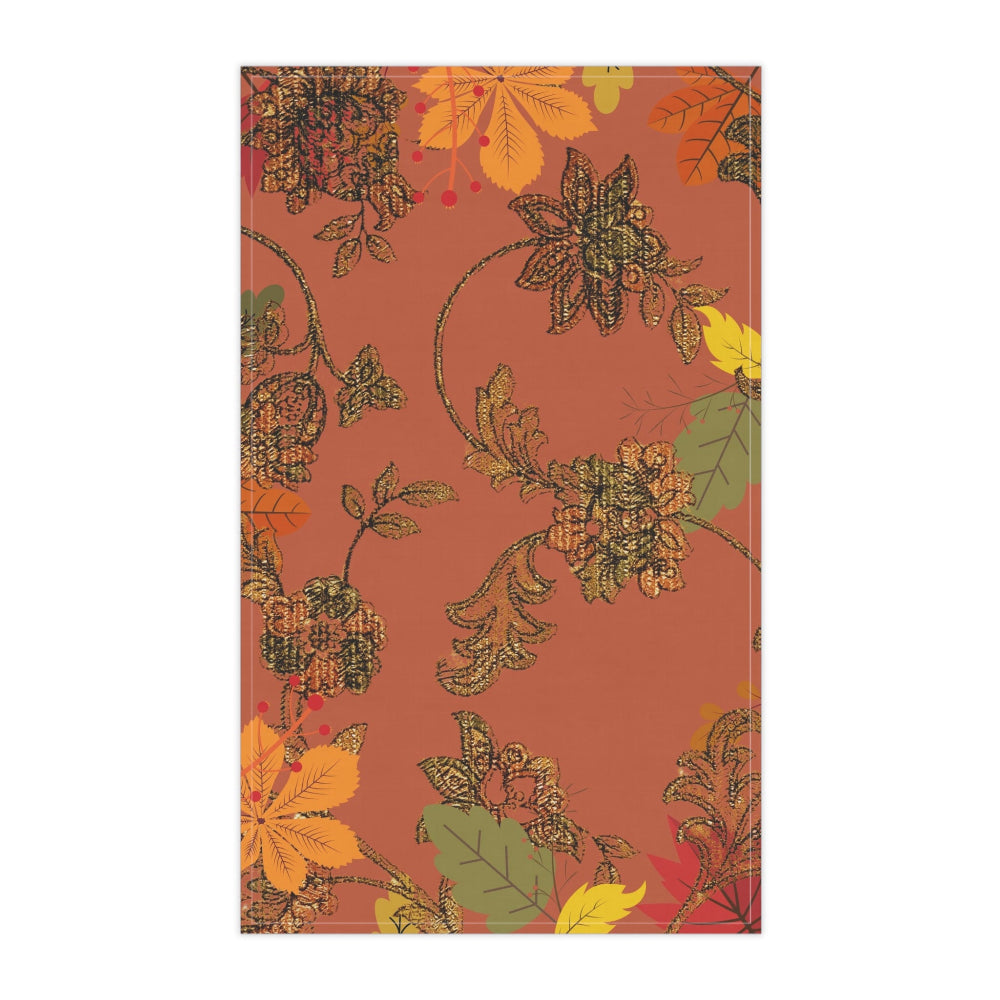 Deep orange background with bronze floral pattern and multi colored fall leaves on a kitchen tea towel shown in detail on a white background