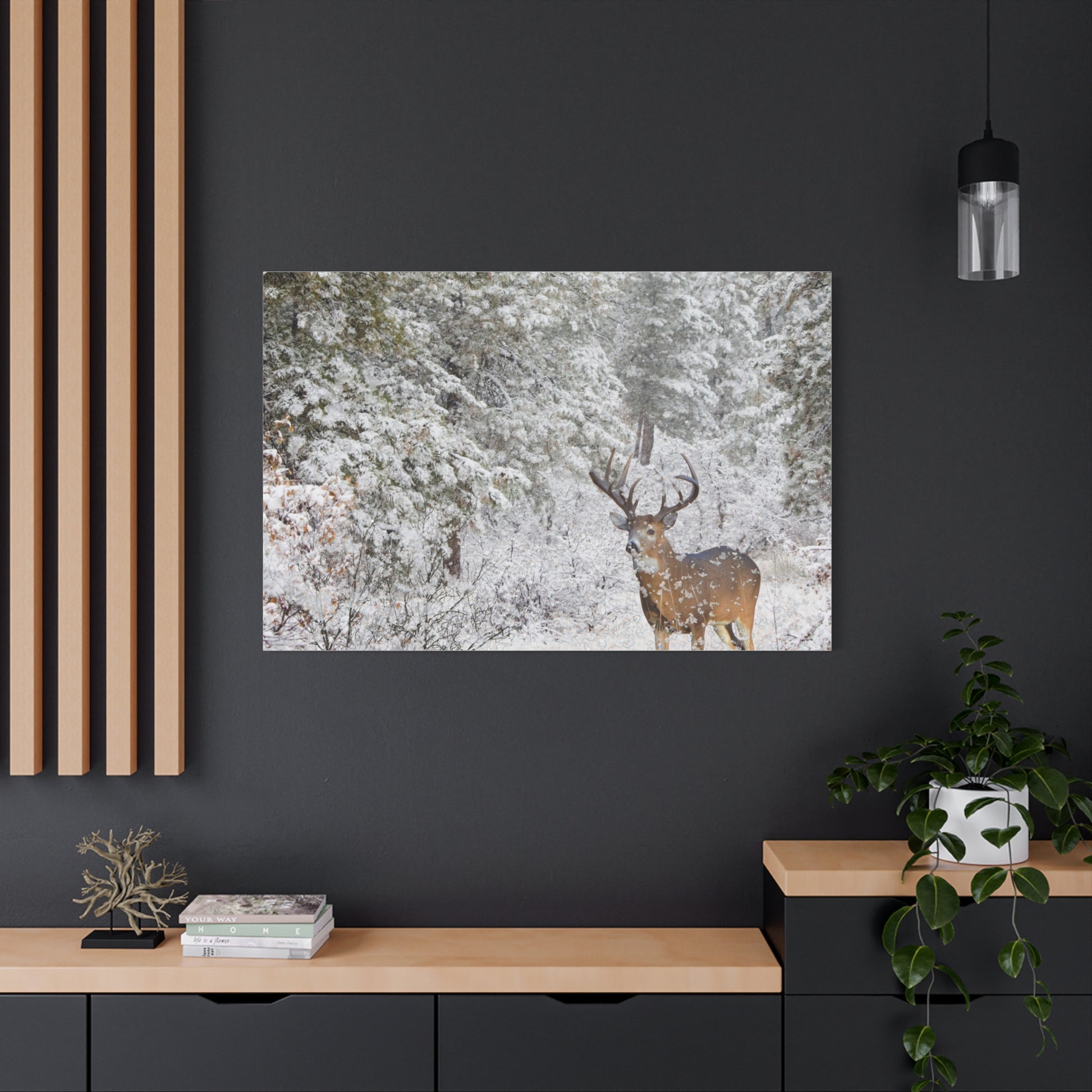 Framed picture of a deer in a snowy forest on a dark wall above a wooden shelf.