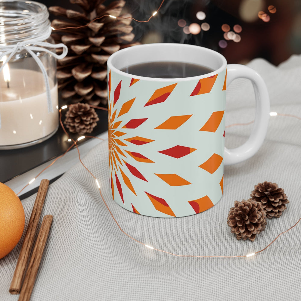 White mug with orange geometric pattern on a table with decorative items