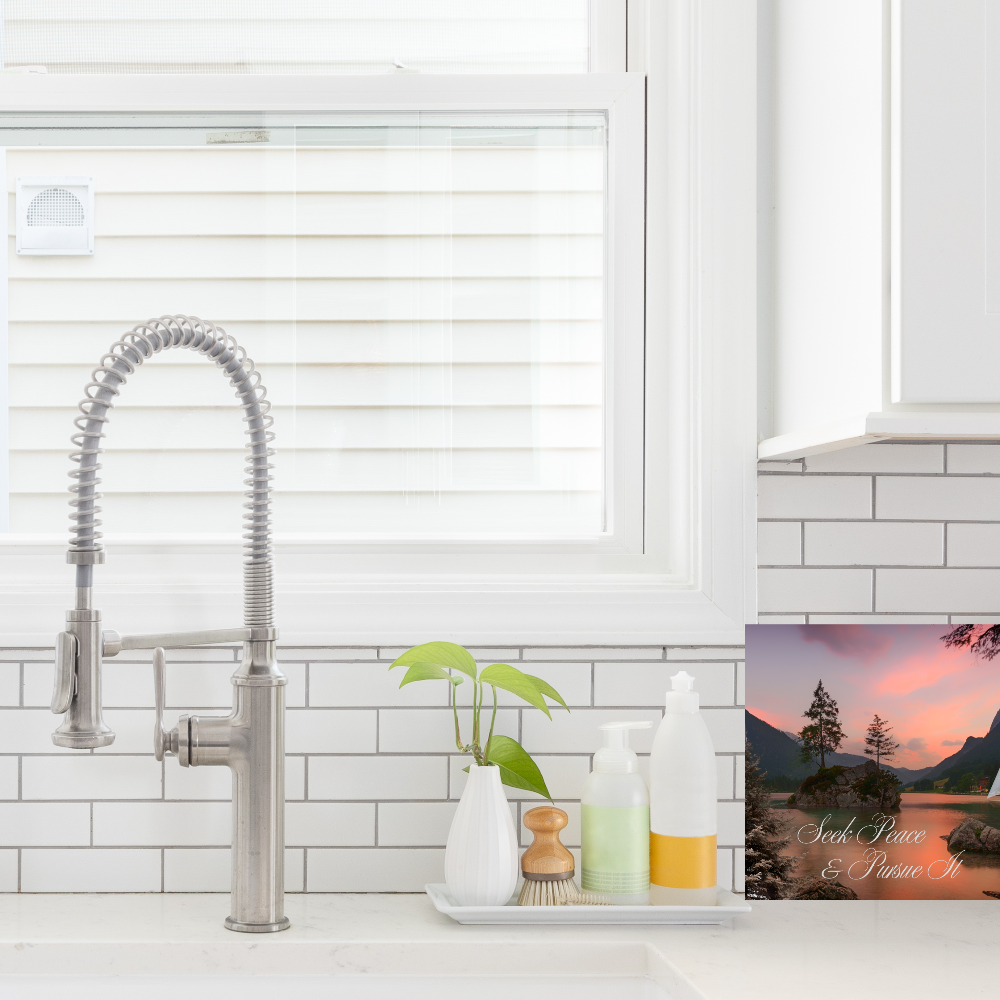 Modern kitchen sink with faucet and decorative items and canvas print with the text Seek Peace and Pursue it on a countertop.