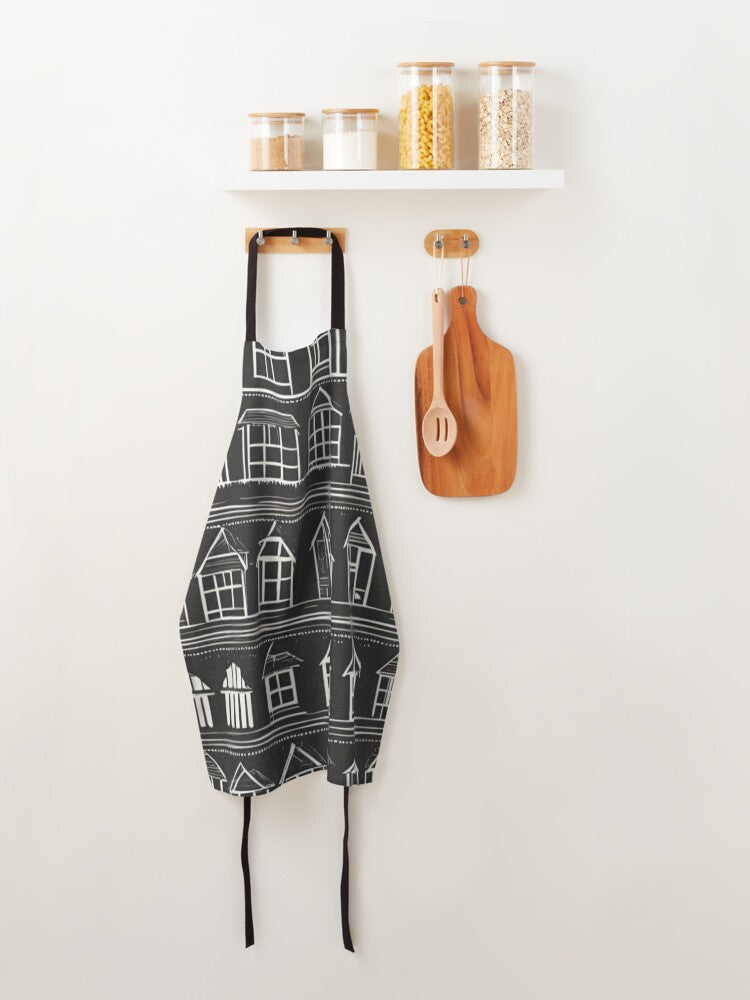 A designer apron with little white houses on a black backround
