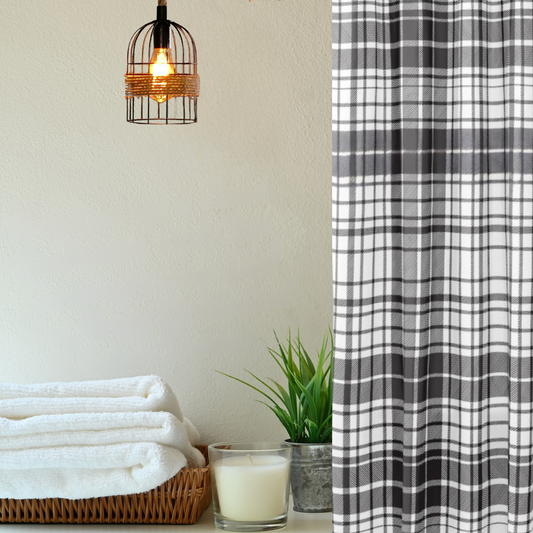 Plaid shower curtain next to folded towels and a candle on a shelf.