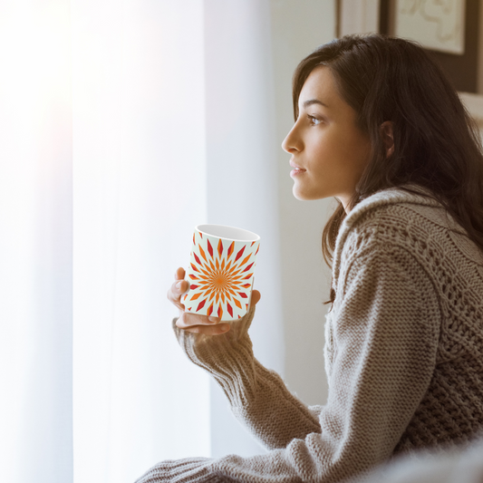 orange starburst mug shown with a woman holding it and looking out of a window
