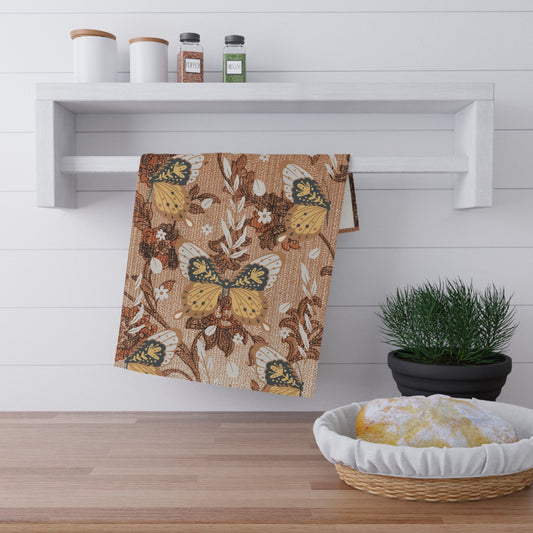 Decorative kitchen towel with butterfly design hanging on a white shelf.