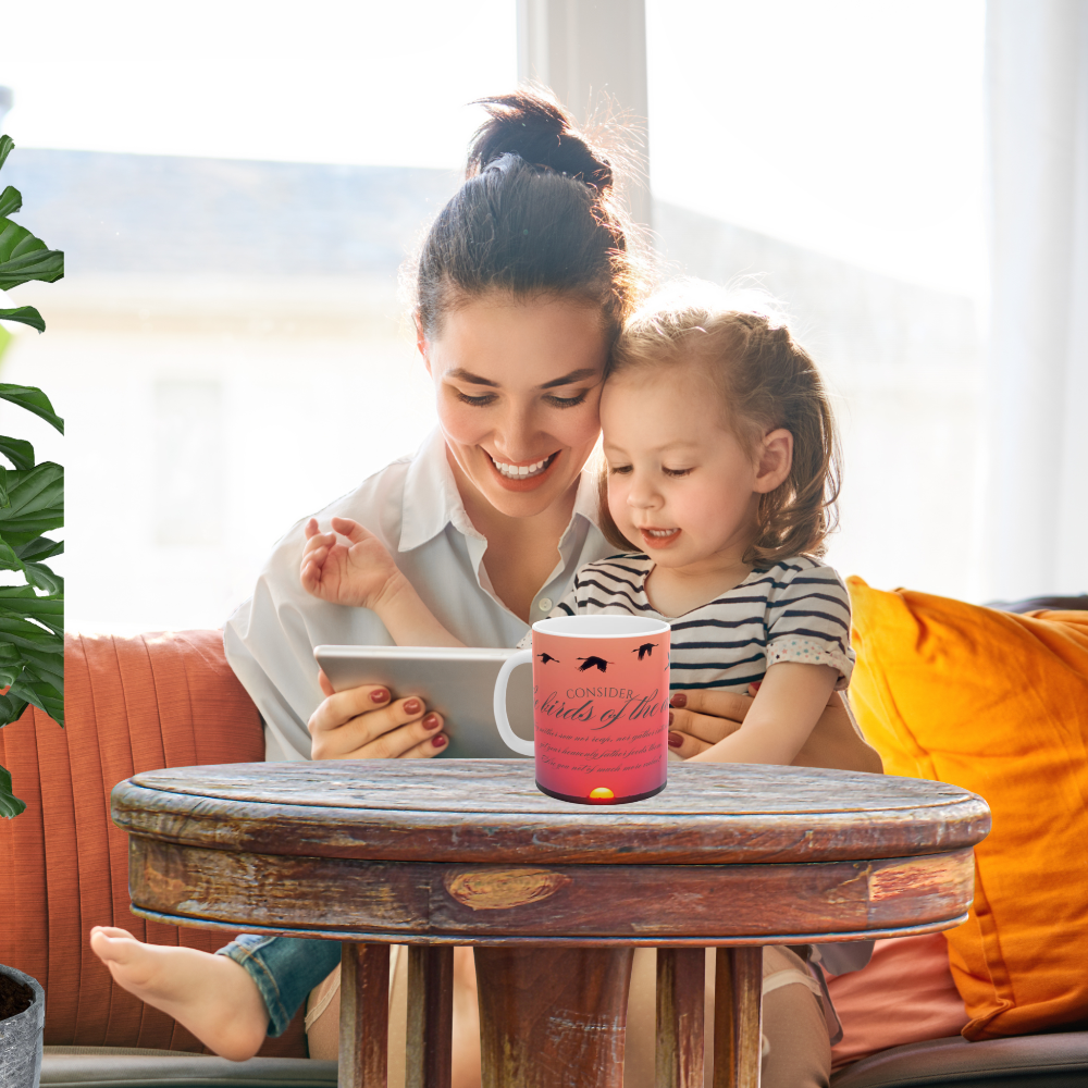 Consider the birds inspirational mug shown on a table with a woman reading to a child