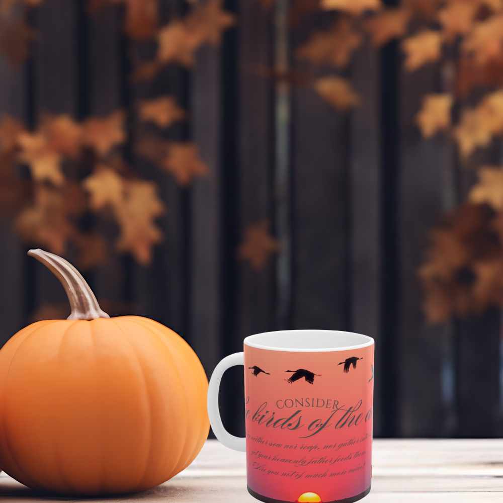 Consider the birds inspirational ceramic coffee mug shown outdoors with a pumpkin