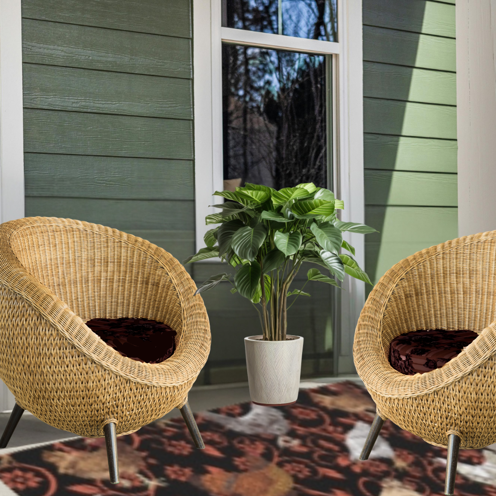 Chicken Outdoor Rug shown with two wicker chairs on a porch with a plant and green siding in the background.