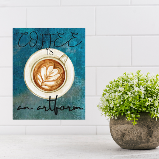 Decorative sign with a coffee cup and text 'Coffee is an artform' on a blue background, placed next to a potted plant.