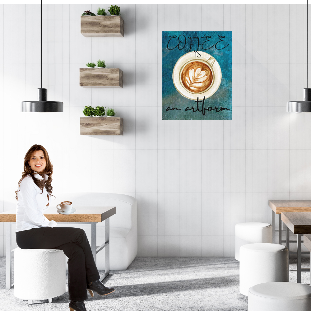 Woman sitting at a table in a modern cafe with a teal colored 'Coffee is an Artform' canvas print on the wall.