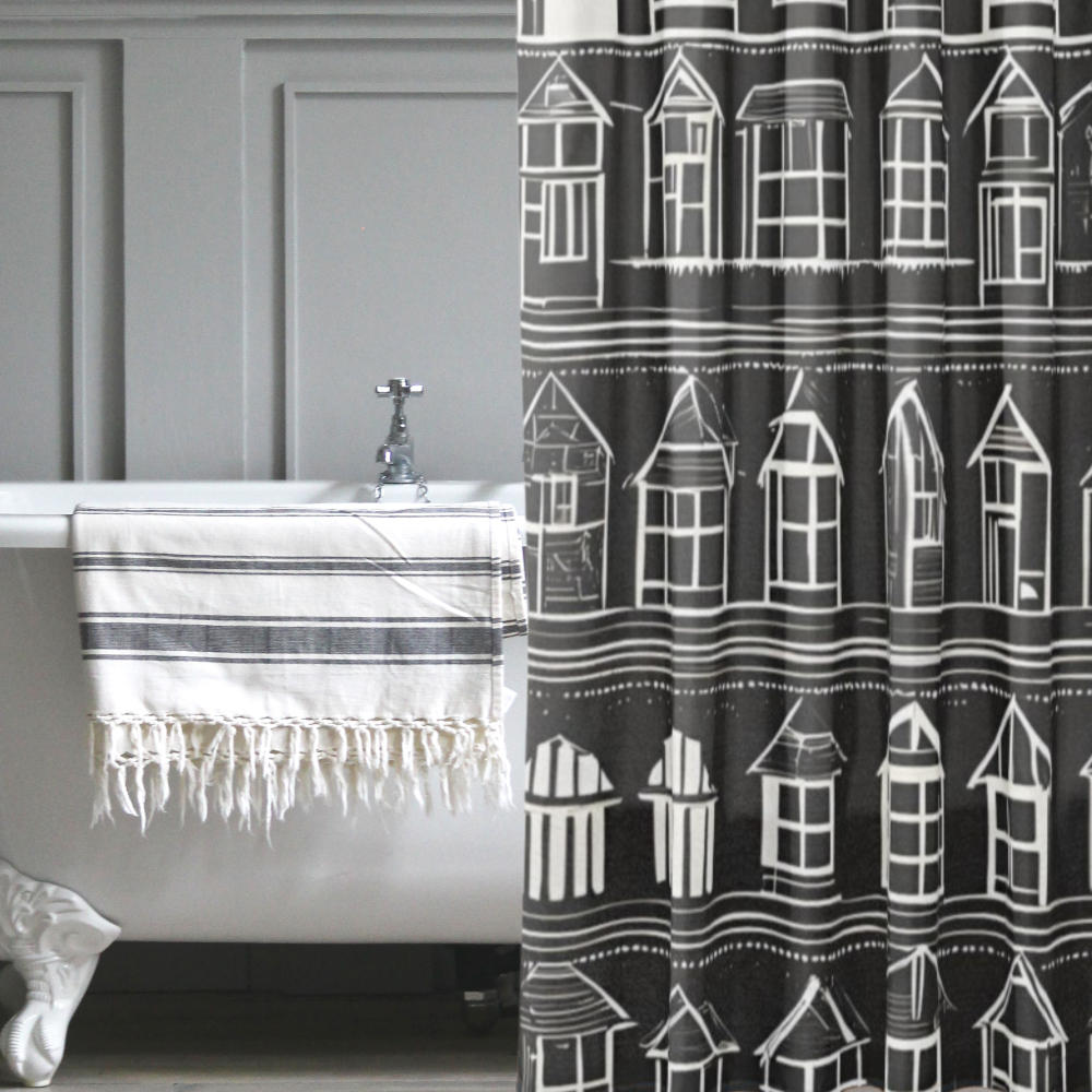 A beautiful black shower curtain with rows of white houses shown in a nostalgic bath setting.