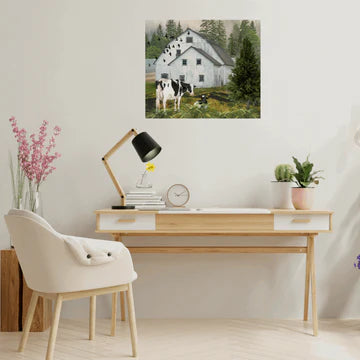 Home office with wooden desk, chair, lamp, and landscape on the wall with Holstein cows