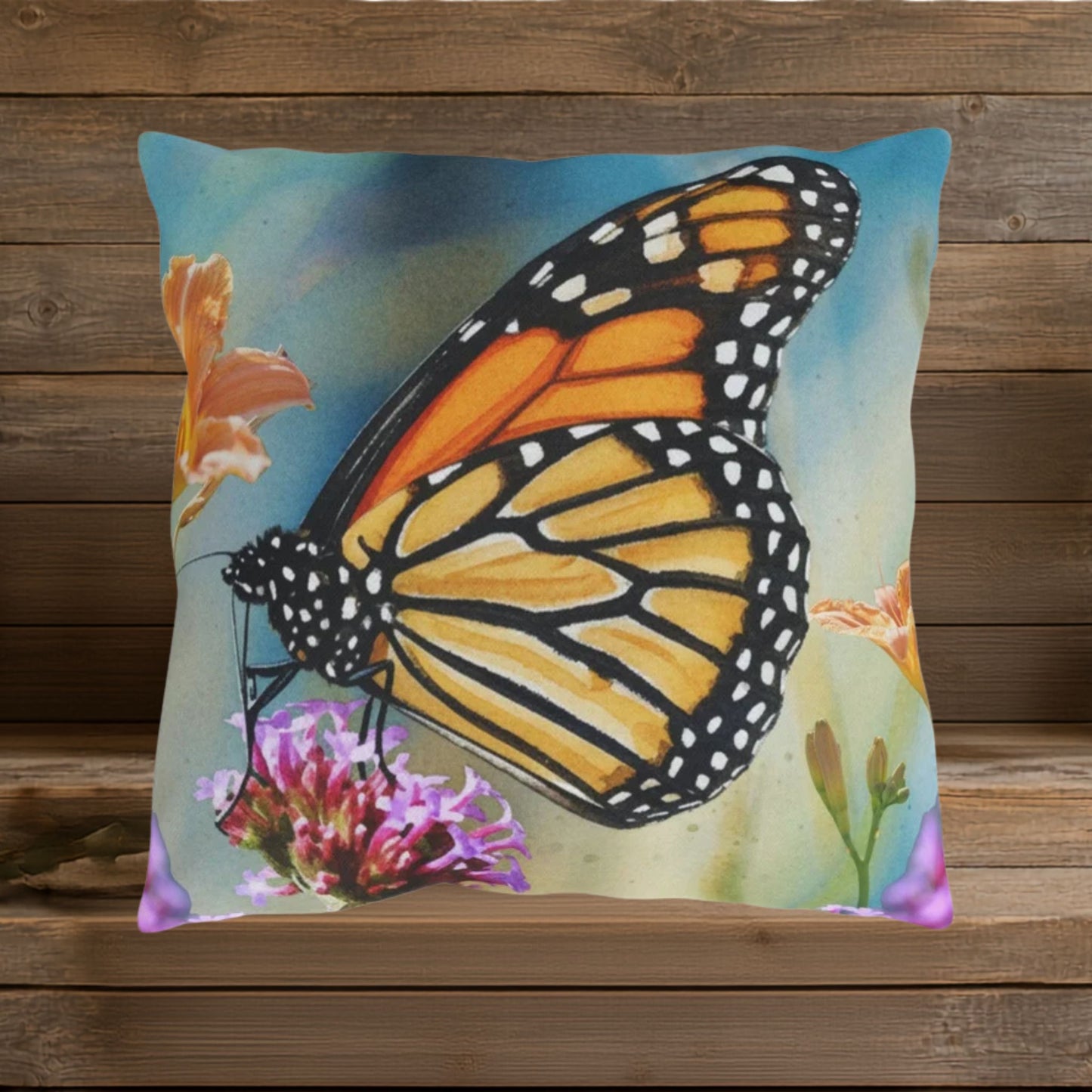 Closeup of design featuring a large, vibrant orange, gold and black butterfly on a watercolor blue background with orange and lavender colored flowers.