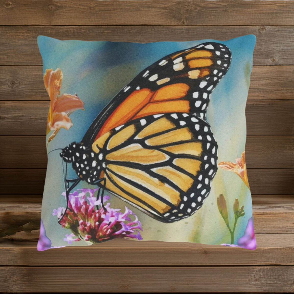 Closeup of design featuring a large, vibrant orange, gold and black butterfly on a watercolor blue background with orange and lavender colored flowers.