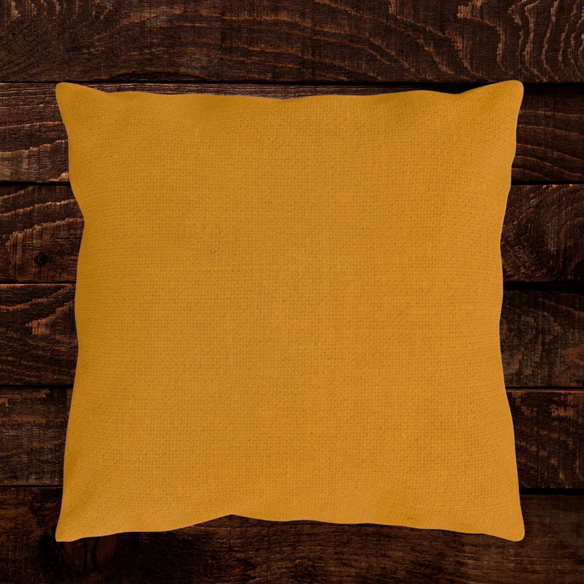 Mustard gold linen-look throw pillow shown on a dark wood background