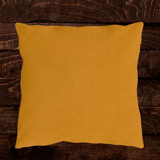 Mustard gold linen-look throw pillow shown on a dark wood background