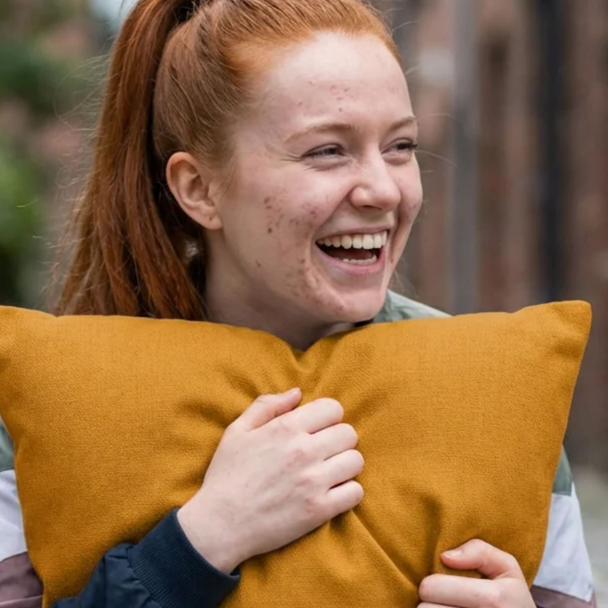 Mustard gold linen-look throw pillow shown with a model holding it.
