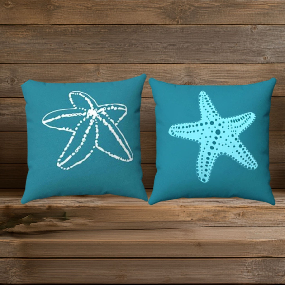 Two square teal throw pillows with different starfish designs shown on a wood background