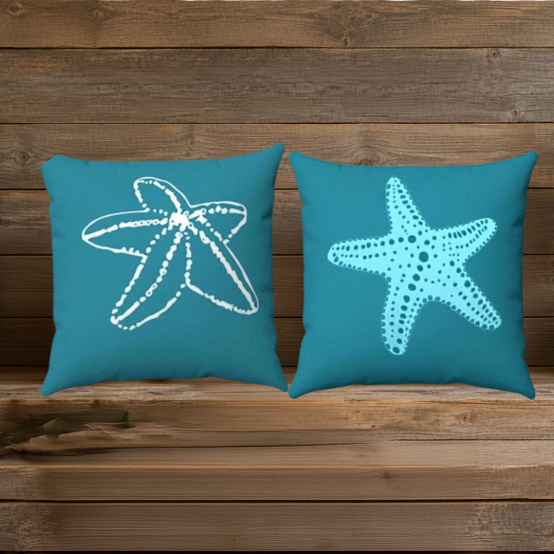 Two square teal throw pillows with different starfish designs shown on a wood background
