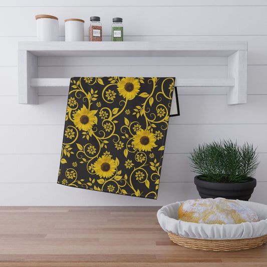 Black towel with yellow sunflower pattern on a wooden surface with a plant and basket in the background.