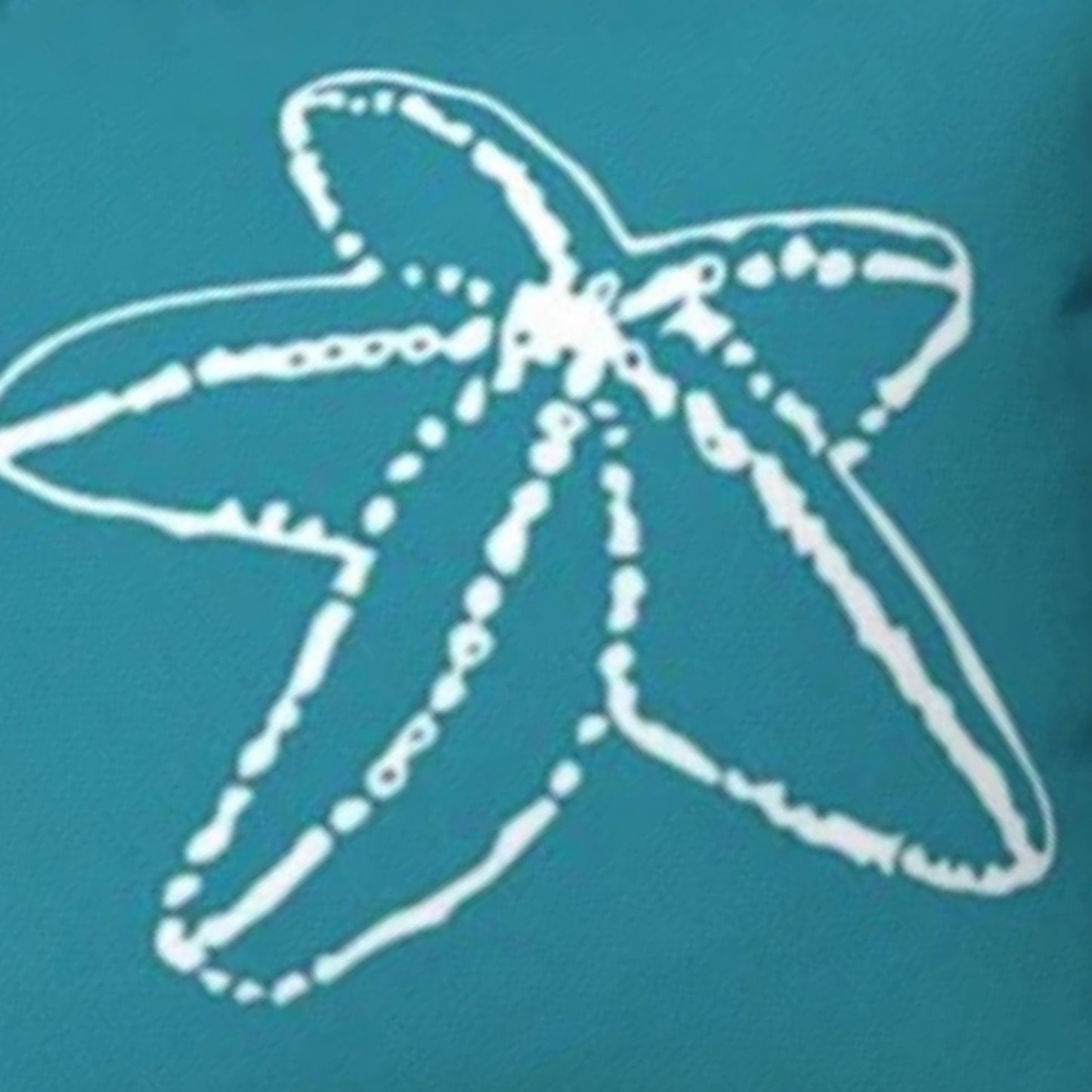 A close-up of a teal pillow with a white hand-drawn starfish outline graphic.