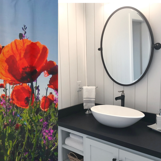 Bathroom with a white sink, black countertop, and round mirror, featuring a colorful floral shower curtain.