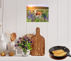 A bright, sunny field of flowers with a red cow shown in metal art print on a kitchen wall