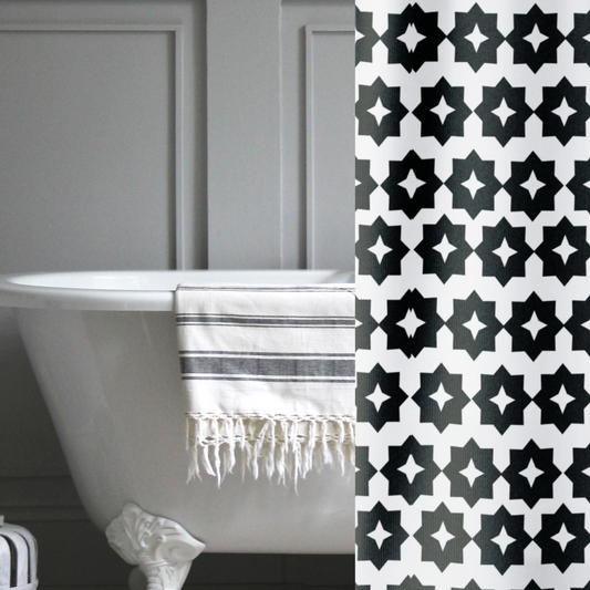 A black and white, crisp geometric shower curtain shown in a gray bathroom